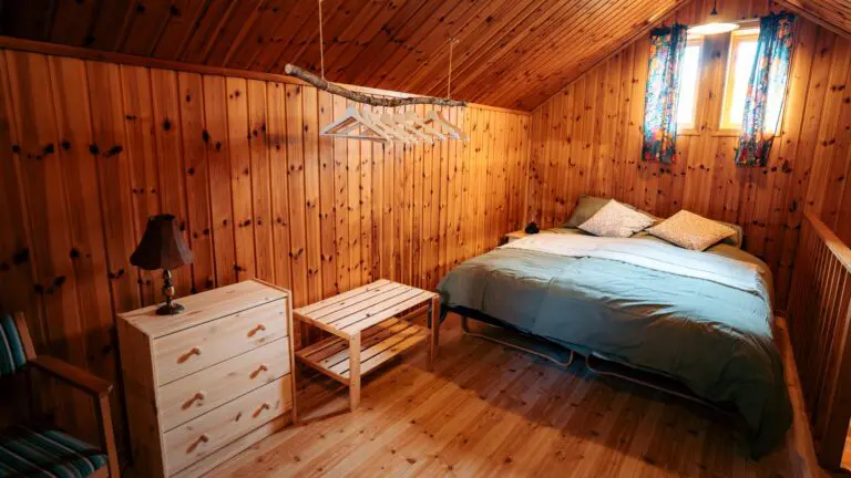 cozy wooden cabin bedroom with bed, dresser, and hangers