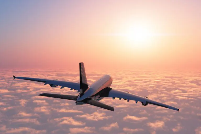 airplane flying above clouds at sunset