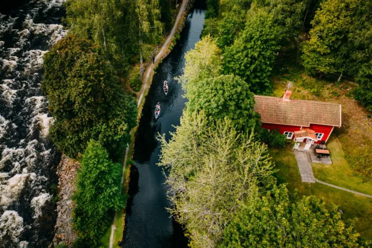 aerial view of two canoes on a canal next to a red house