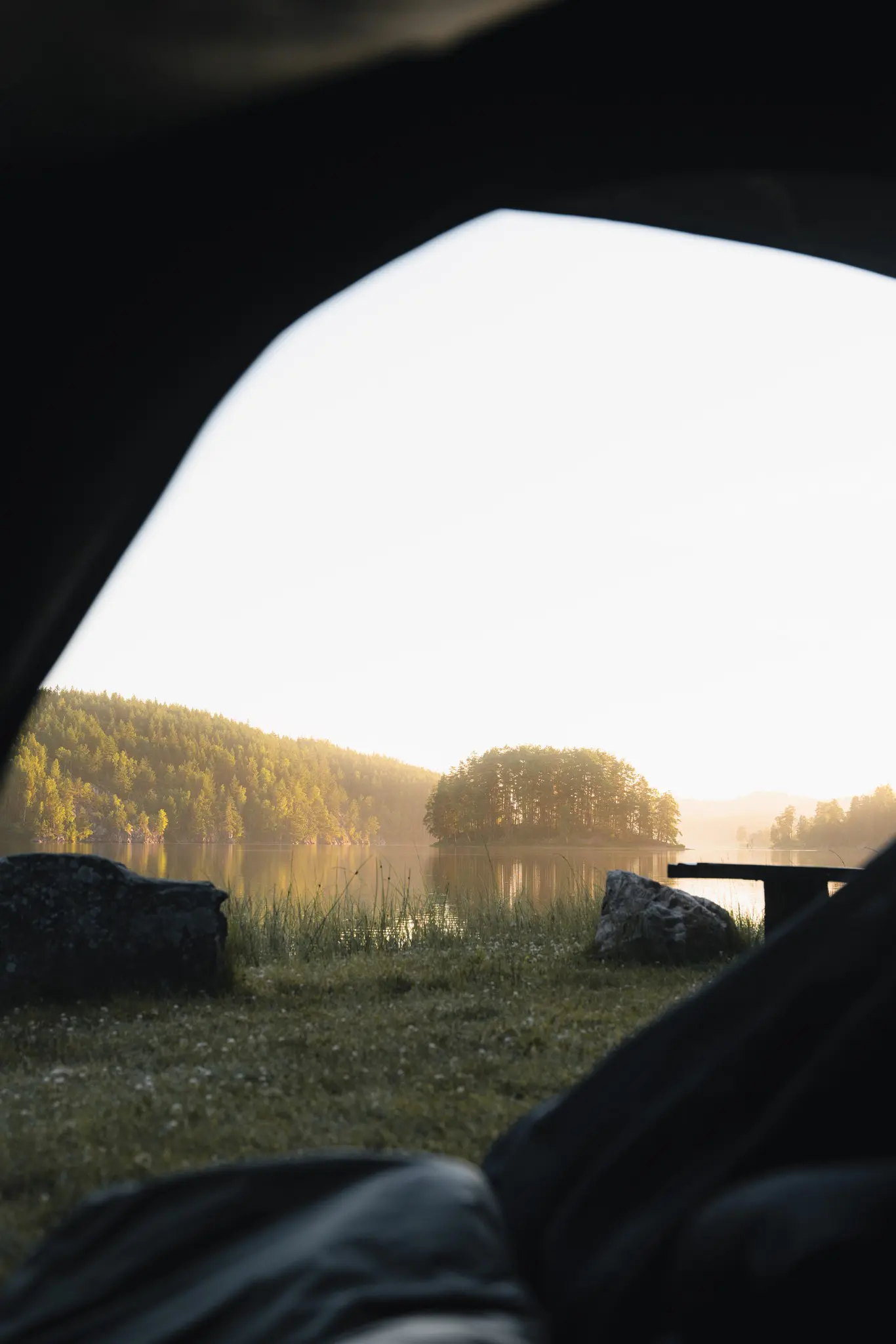view from inside a tent overlooking a lake at sunrise